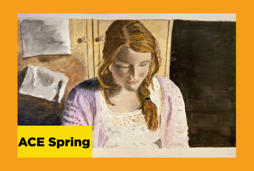 an auburn haired girl sits against a cupboard looking down at something 
