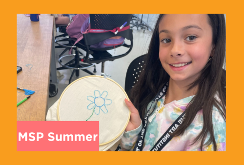 a young girl shows off a flower she is emboidering with blue thread