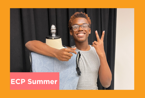 a student throws up a piece sign next to their fabric draped on a dress form