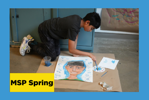 Boy kneeling on the floor over a self portrait painting he is working on