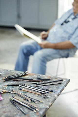man drawing with pencils in foreground