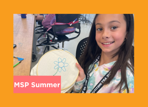 a young girl shows off a flower she is emboidering with blue thread