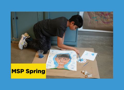 Boy kneeling on the floor over a self portrait painting he is working on